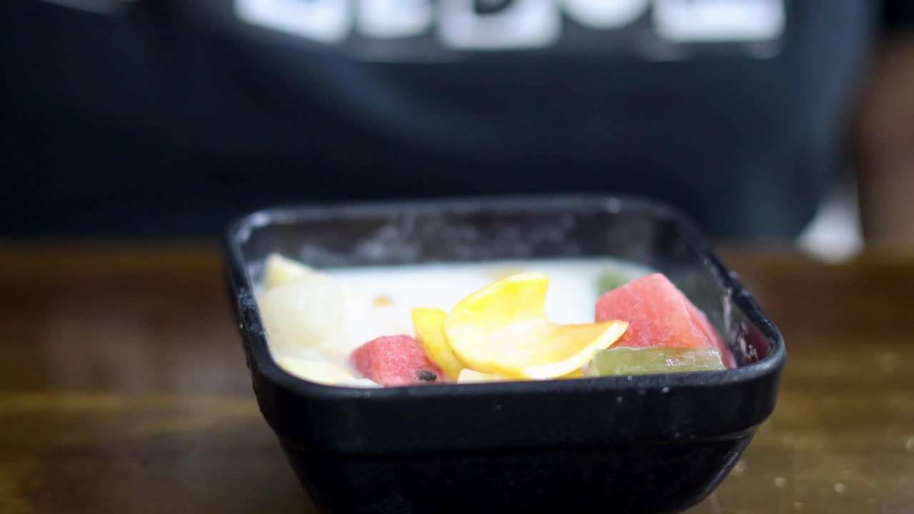 persona saboreando un colorido postre de frutas