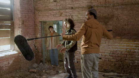 man production worker holding a microphone on a movie recording in a ruined building 1