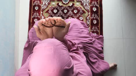 muslim woman praying on a prayer rug