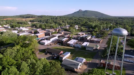 aerial-slow-push-into-pilot-mountain-nc,-north-carolina-with-pilot-mountain-in-the-background-and-water-tower-in-the-foreground