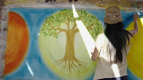 artist painting a vibrant tree of life mural at an outdoor event