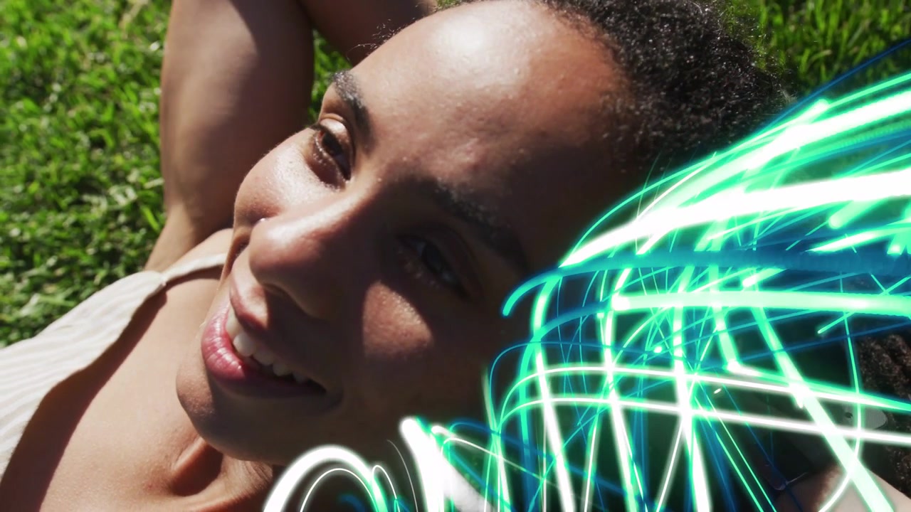 Strisce al neon che appaiono, mostrando una donna sdraiata sull'erba verde, che alza le braccia e sorride per il marketing.