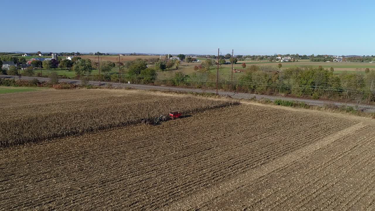 vista aérea de un granjero amish cosechando su cosecha de otoño de maíz con cinco caballos tirando de su cosechadora en un soleado día de otoño