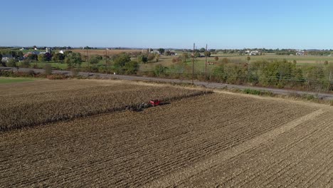 aerial view of an amish farmer harvesting his autumn crop of corn with five horses pulling his harvester on a sunny autumn day