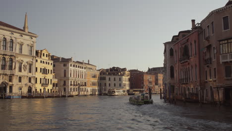 wide shot of a small boat cruising through morning canal grande in venice, italy