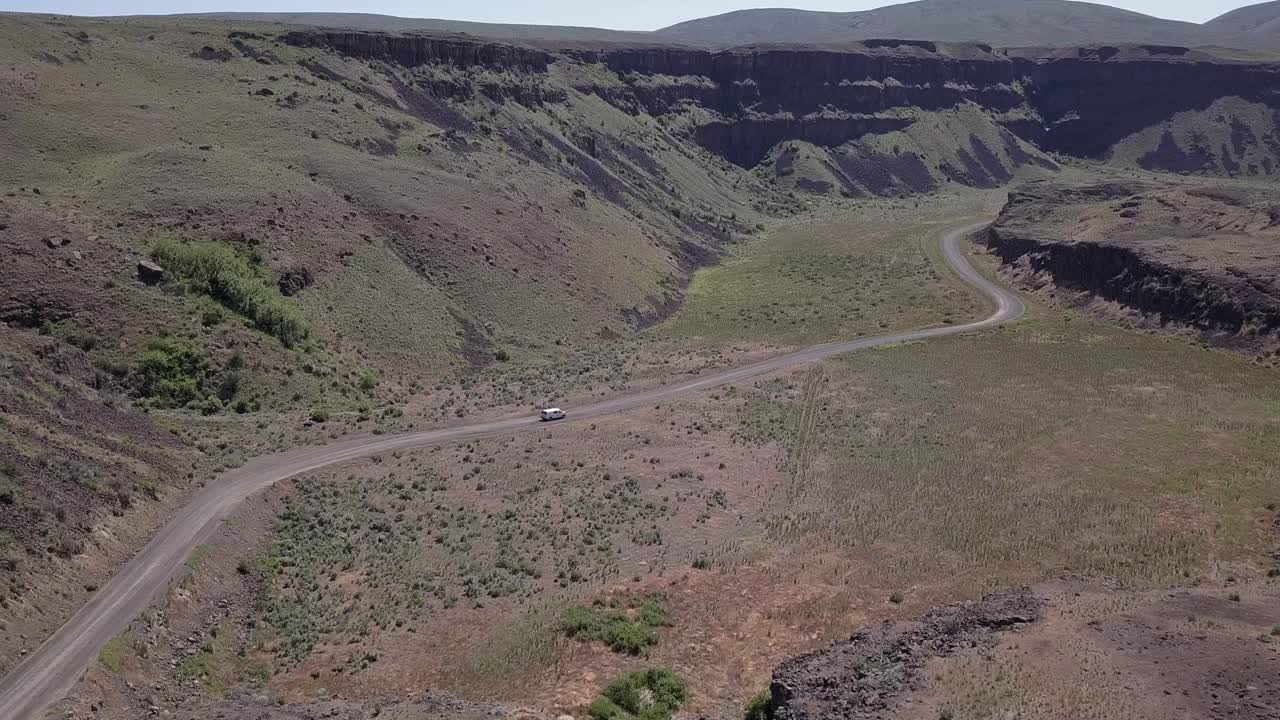 vista aérea: la furgoneta conduce por un camino sinuoso en las tierras de moses coulee