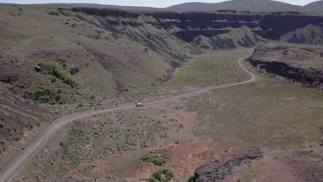 Aerial-view:-Van-drives-winding-road-into-Moses-Coulee-scablands