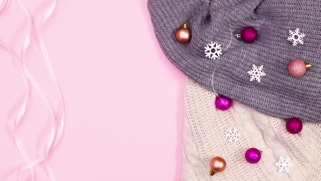 christmas winter decoration with knitted sweaters and ornaments and ribbons on pink theme. stop motion