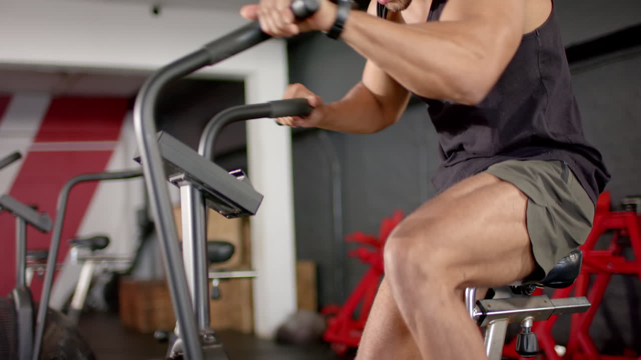 Uomo che si allena intensamente in palestra usando una cyclette per un allenamento cardio.