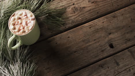 video of mug of chocolate with marshmallows, decorations and copy space on wooden background