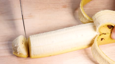 a banana being sliced with a knife