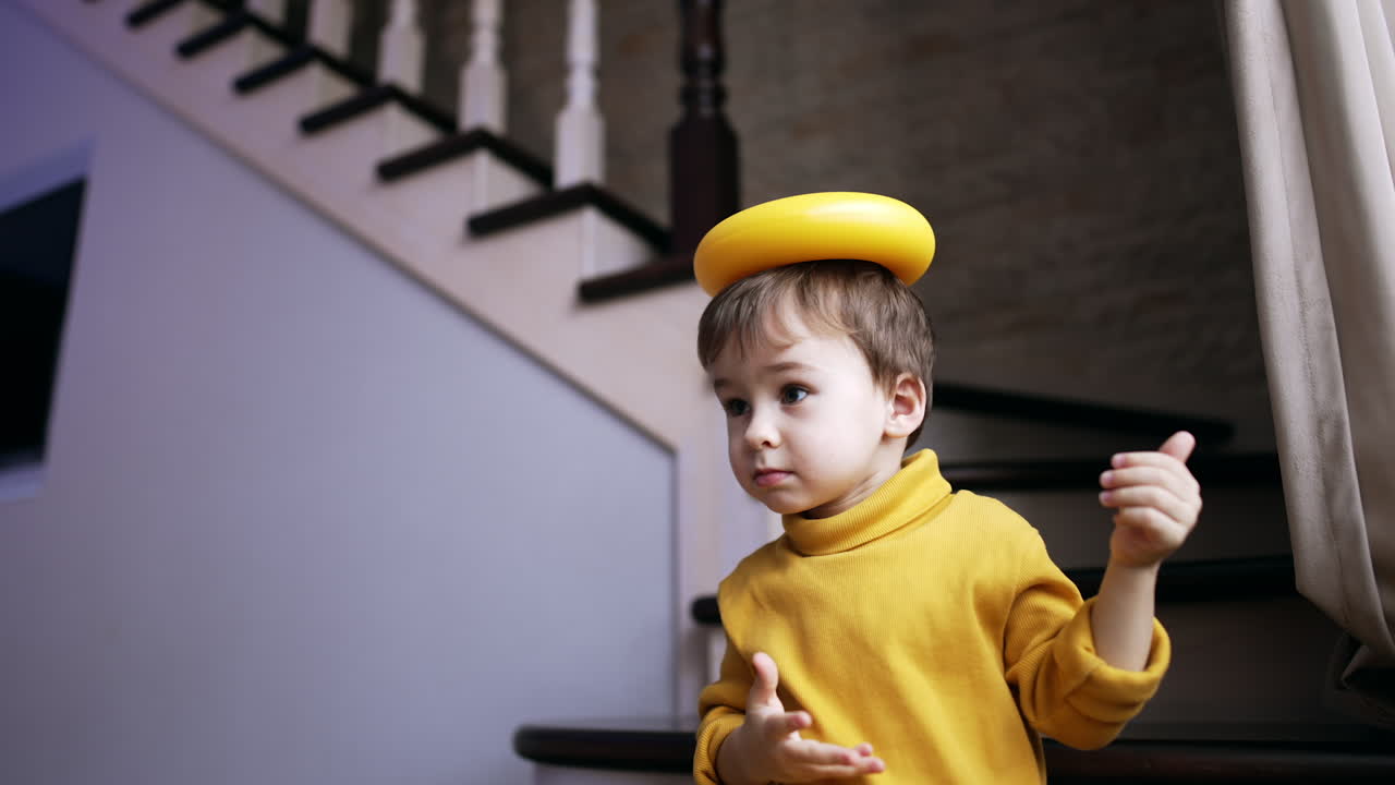 Smiling cute baby boy holding a ring from pyramid on the head. Happy child playing at home.