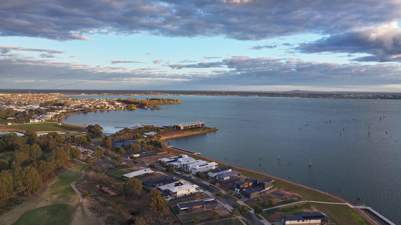 Golf course and nearby homes sit beside Lake Mulwala under soft evening sky and clouds