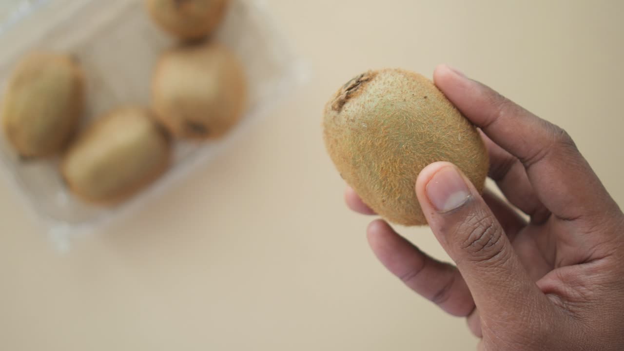 Hand holding a kiwi fruit