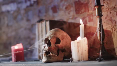 video of stack of books with spider web, skull and candles on brick wall background