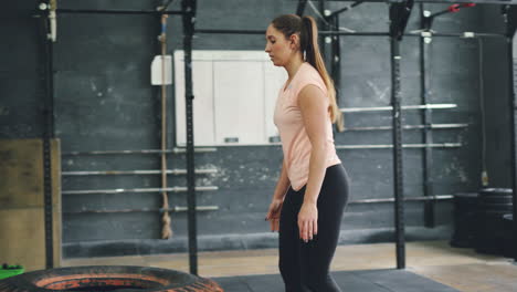woman performing tire flip exercise in gym