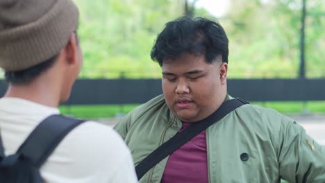 two asian college students talking at the campus park