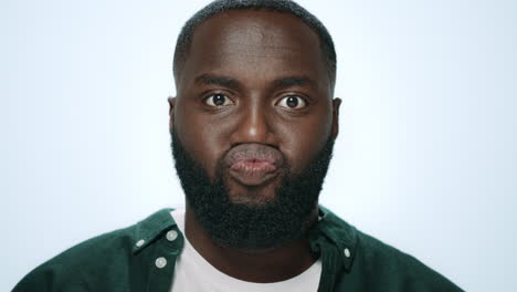 retrato de un hombre africano positivo haciendo caras divertidas en un fondo gris.