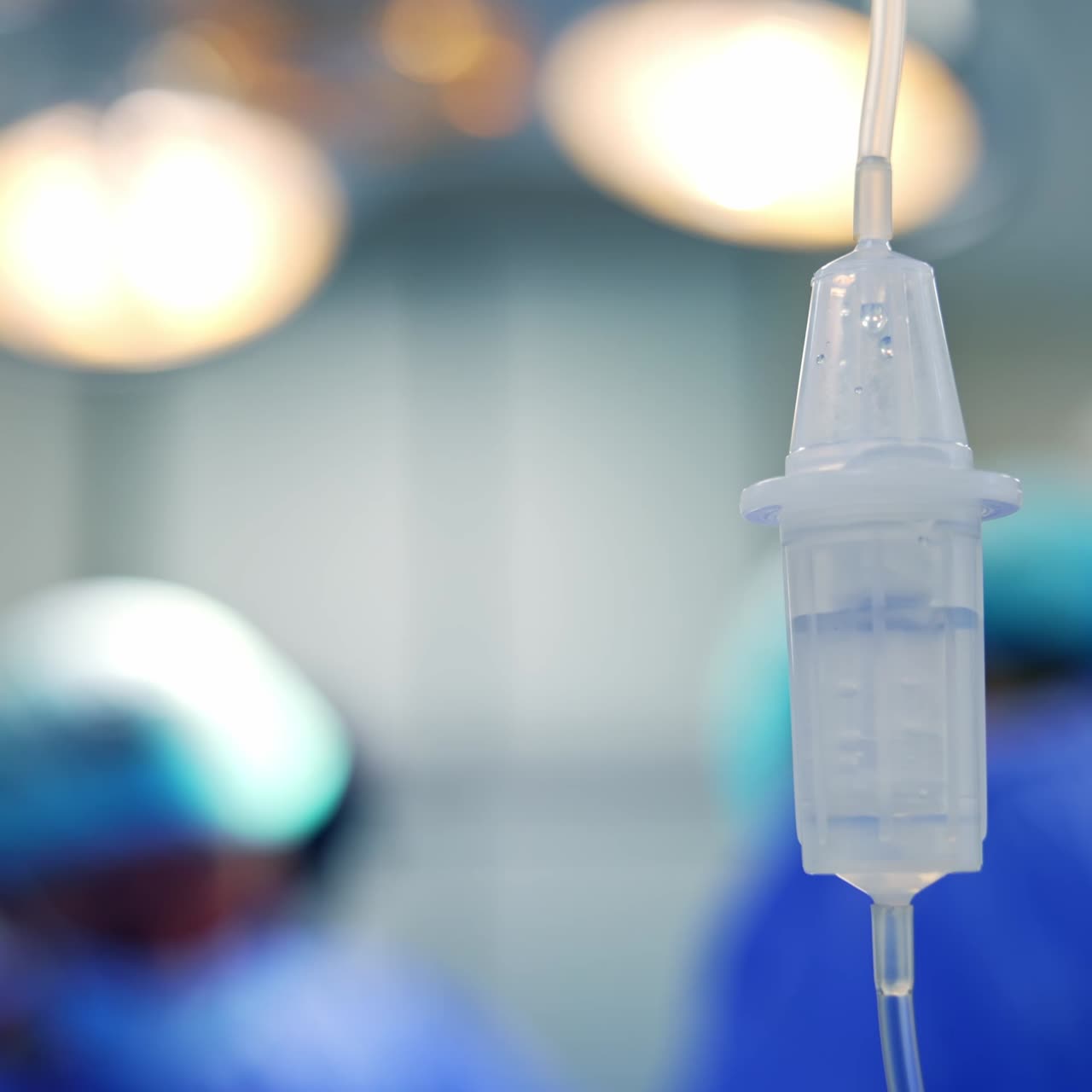 Drop counter reservoir filled with liquid. Medicines dripping in the dropper at surgery room. Close up. Blurred backdrop