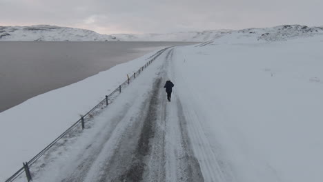 Frau-Läuft-Im-Winter-In-Zeitlupe-Auf-Verschneiter-Straße,-Dolly-Vorwärts