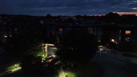 Bandera-Estadounidense-Por-La-Noche-En-Una-Zona-De-Viviendas-Para-Jubilados-Desarrollada-En-Un-Suburbio-Estadounidense