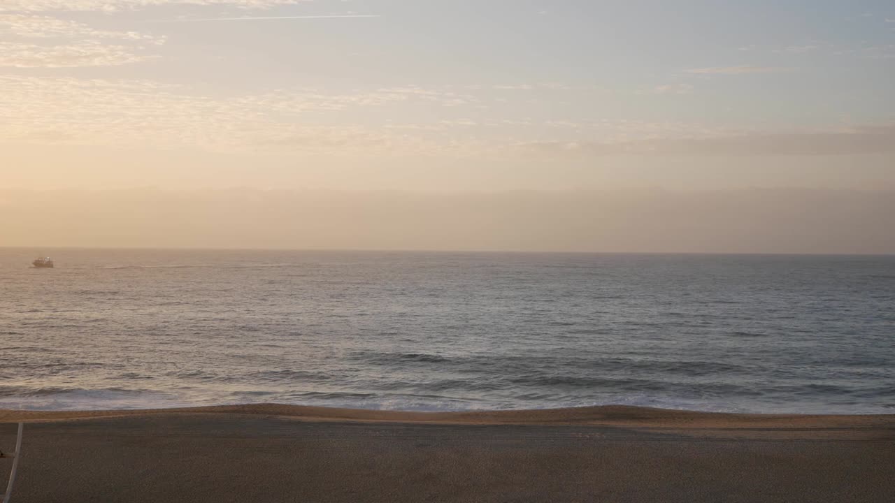 Panoramic horizon landscape sunset. Sky has golden light and beautiful cumulus cloud streets. Calm sea and fishing boat close to skyline. Waves formation on beachfront, crash