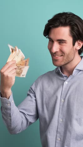 cheerful rich man counting euro banknotes in blue studio
