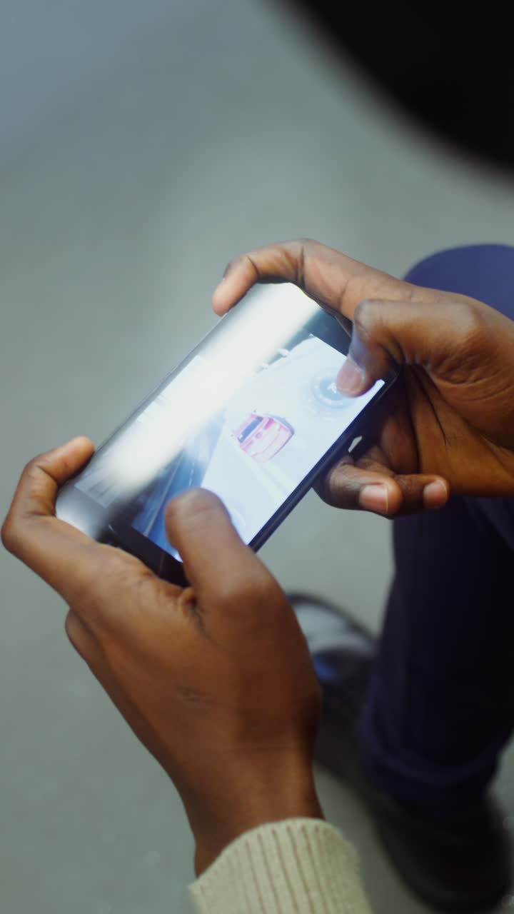 Person playing car racing game on mobile phone