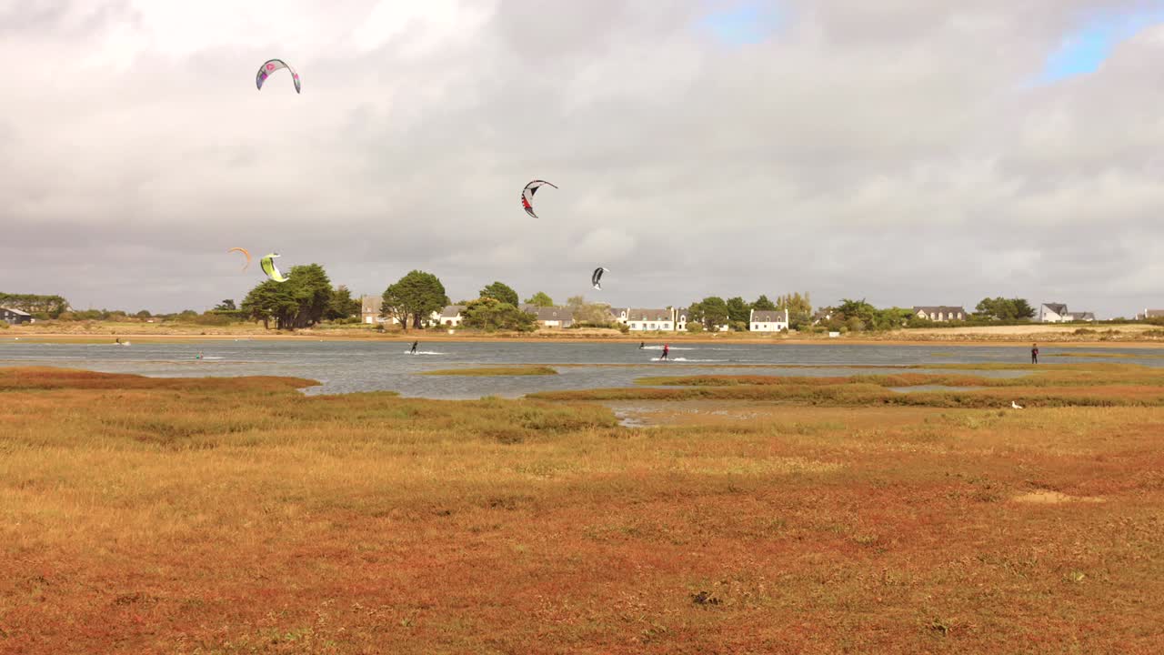 Kite surfers skillfully navigate the calm waters of a picturesque lake, showcasing their agility and enthusiasm