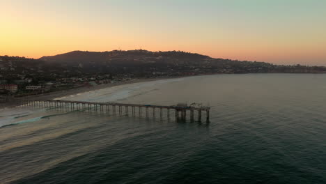 flying towards scripps pier over tranquil ocean in la jolla, san diego during sunrise