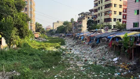 environment pollution, trash pile beside slum in urban city - panning shot