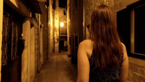 woman walking old town narrow street at summer evening with street lights