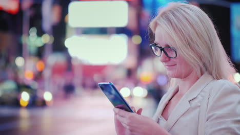 Business-Woman-Uses-A-Smartphone-On-Busy-Times-Square-In-New-York-The-Famous-Yellow-Cabs-Are-Passing