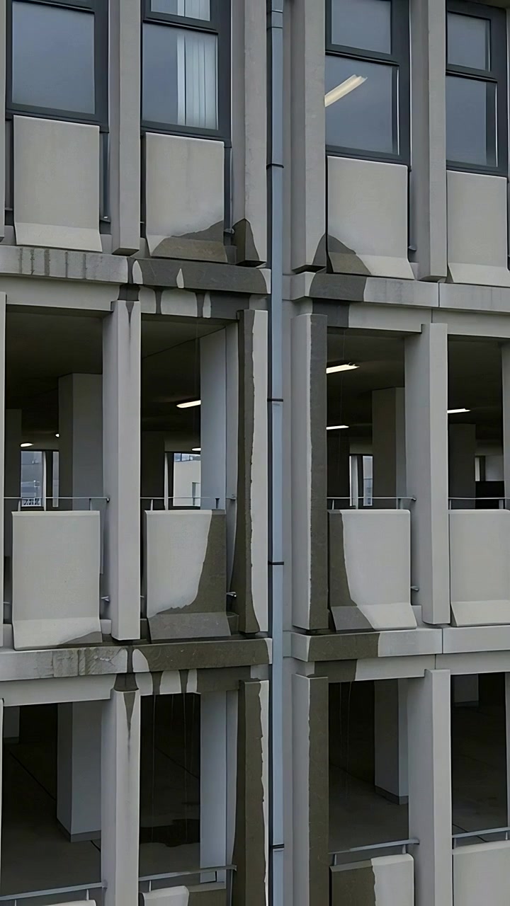 Video verticale: telecamera che si inclina inquadrando la facciata di un parcheggio da vicino, mostrando il tubo di scarico e le macchie