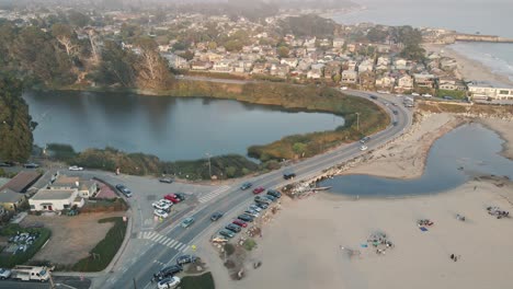 a slow-motion drone shot strafing a road near a peaceful, beachside santa cruz california community with expensive residential houses and short term rentals next to the small craft harbor at sunset