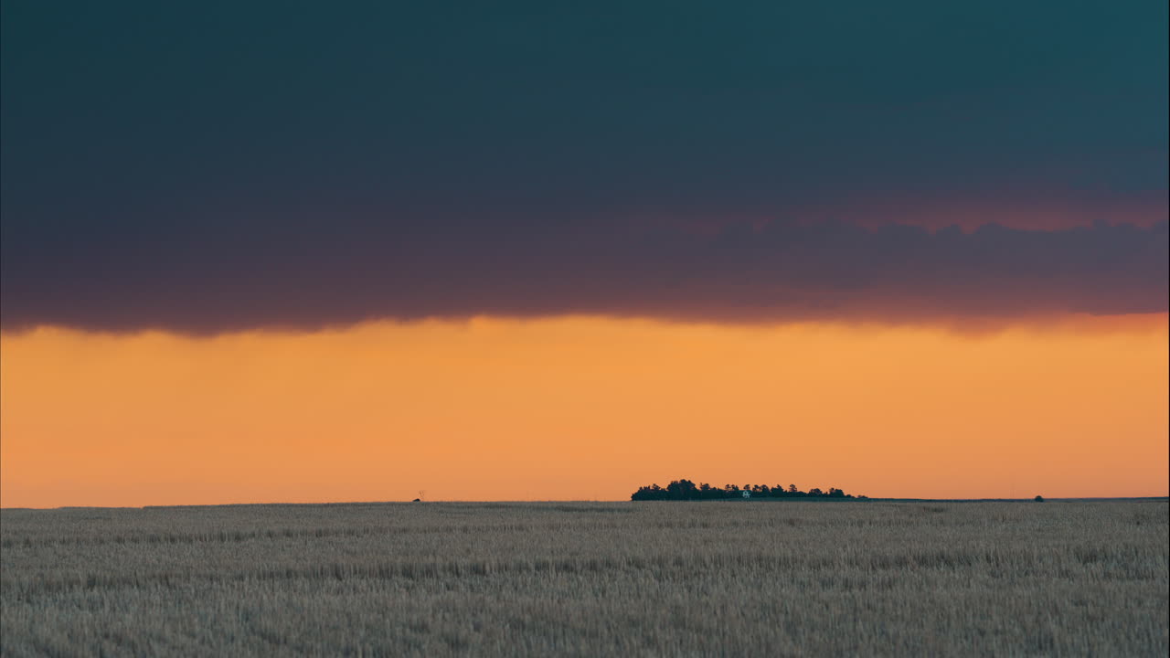 Sunset over farmed fields with peaceful clouds moving past