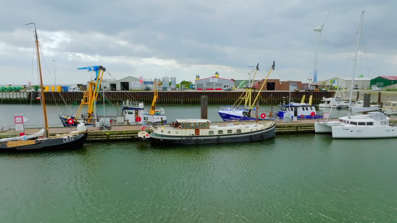 Fishing vessels and leisure boats moored at the harbor in Borkum near Westerems strait. Aerial orbit view.
