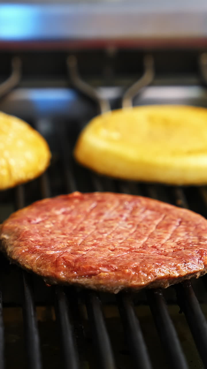 Frying meat and burgers on stove. Preparing burger and beef for hamburger. Cooking hamburger on hot grill pan in fast food restaurant. Close-up. Vertical video