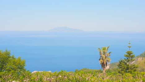 high angle shot from over ischia island with silhouette of the island of capri in the distance in italy on a sunny day