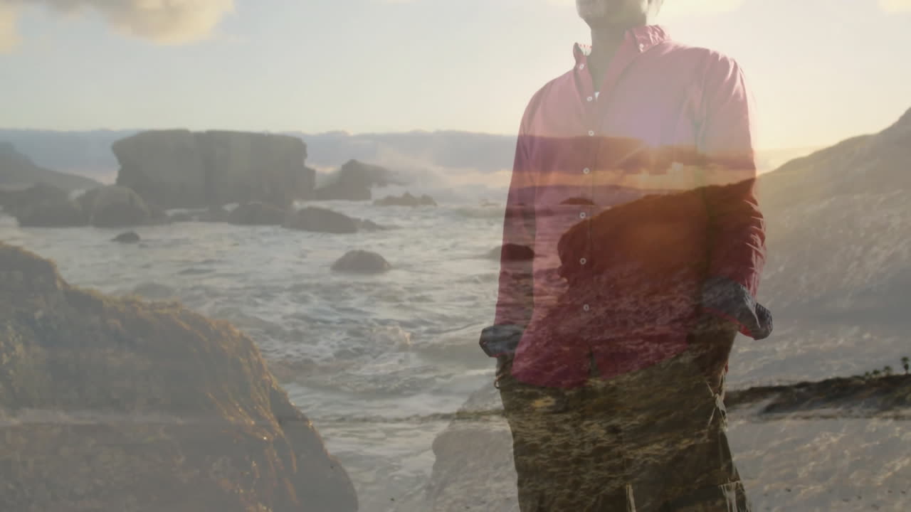Senior man standing on rocky coastline at sunset, overlaying animated sea and sky for marketing