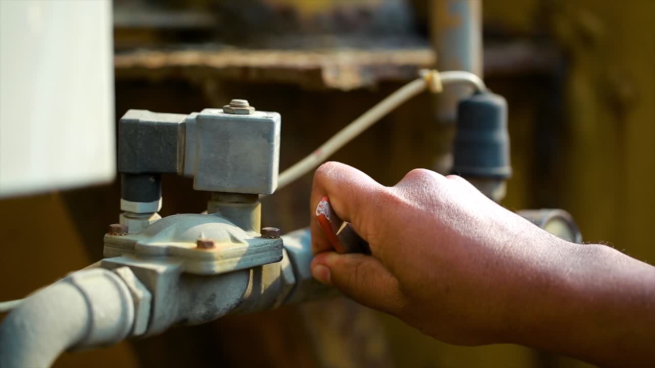제어 생산 공정을 위해 아스팔트 공장에서 생산 작업자가 볼 밸브를 닫습니다.