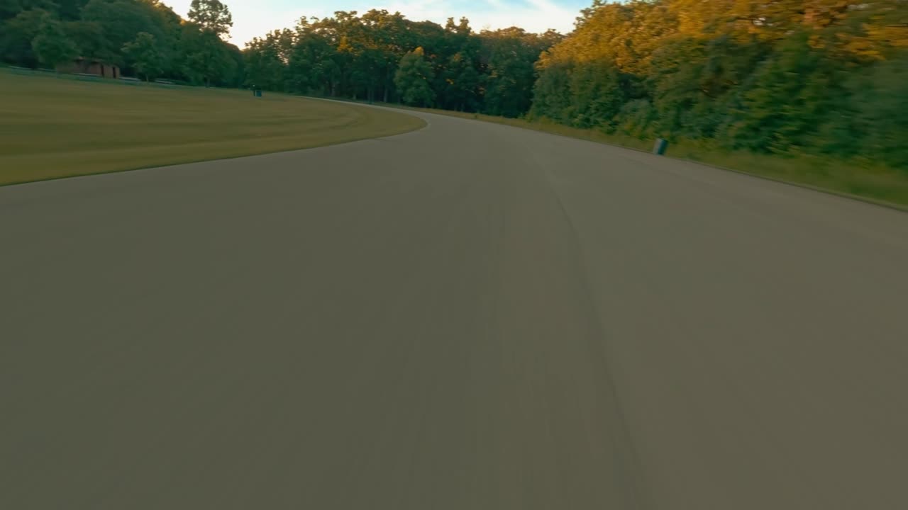 Vibrant drone footage of swift flight over road with ascent to breathtaking sunset panorama of forest from aerial POV