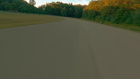 imágenes vibrantes de drones de un vuelo rápido sobre la carretera con ascenso al impresionante panorama de la puesta de sol del bosque desde el punto de vista aéreo