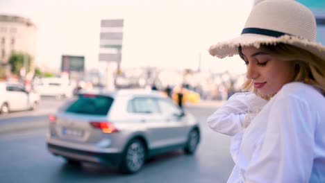 slow motion:young beautiful girl stands by busy road with traffic on background