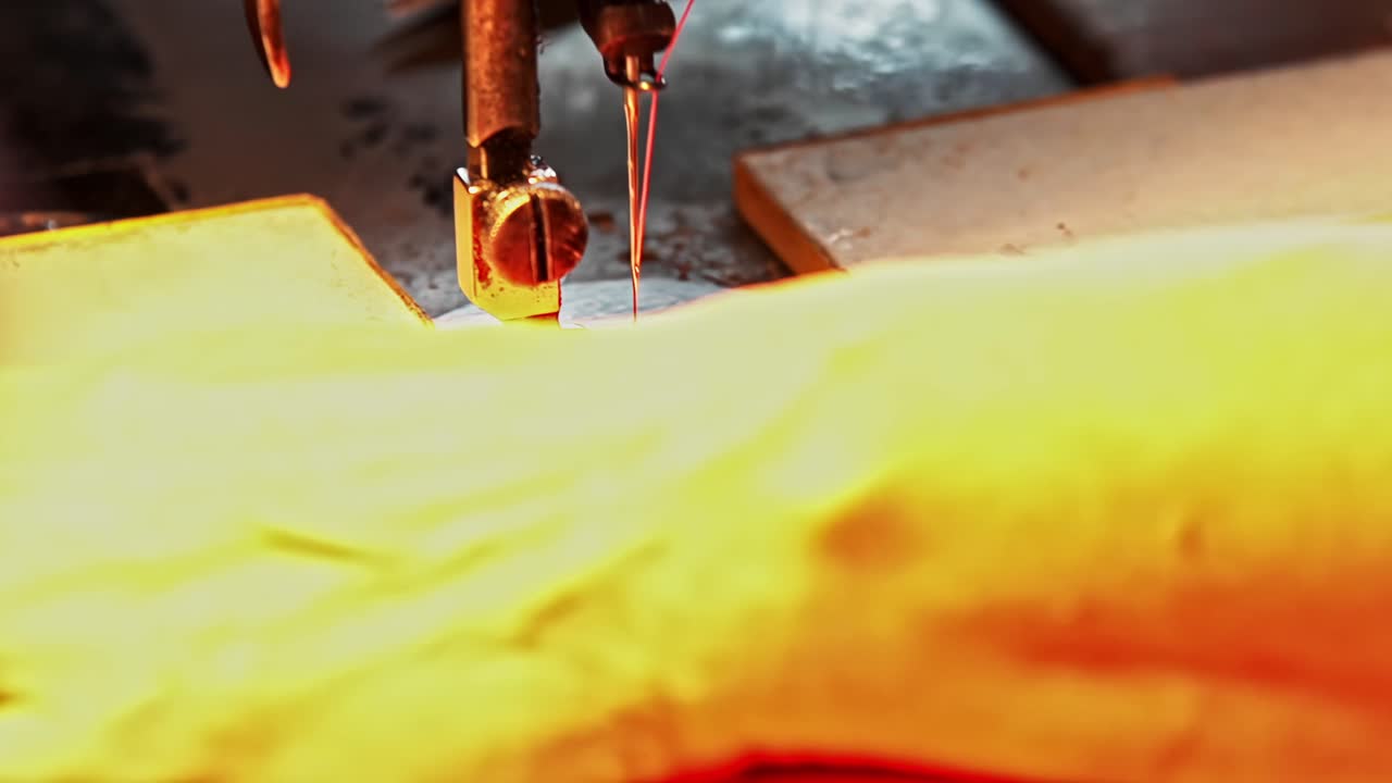 Primo piano delle mani di alcuni operai che guidano un tessuto di pelle attraverso un macchinario con ago e filo per cucire, creando cuciture dettagliate all'interno di un laboratorio di abbigliamento, un'industria di produzione artigianale e tessile