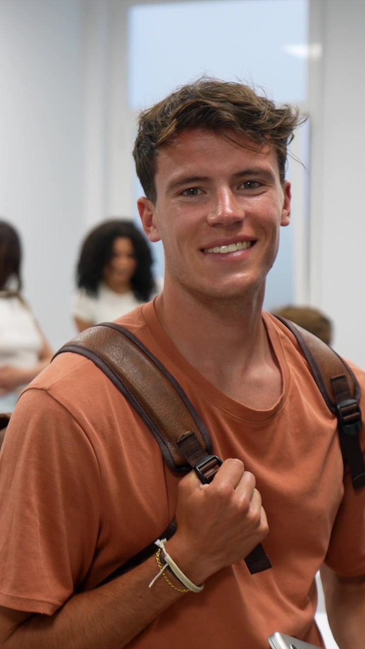 Giovane studente sorridente con zaino e laptop