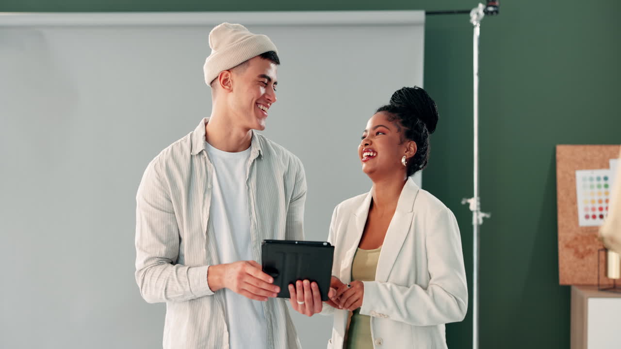 A man and woman discussing on a tablet in a studio
