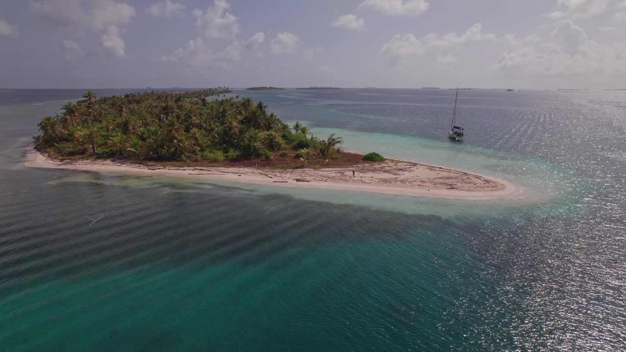 drone disparado desde una isla remota en el archipiélago de san blas con una mujer caminando en la costa
