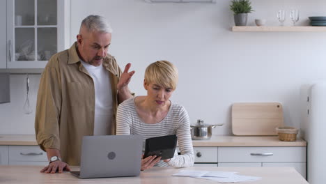 couple arguing over bills in kitchen