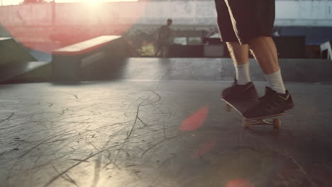 sporty man training skills on skate board at sunset in urban skate park.